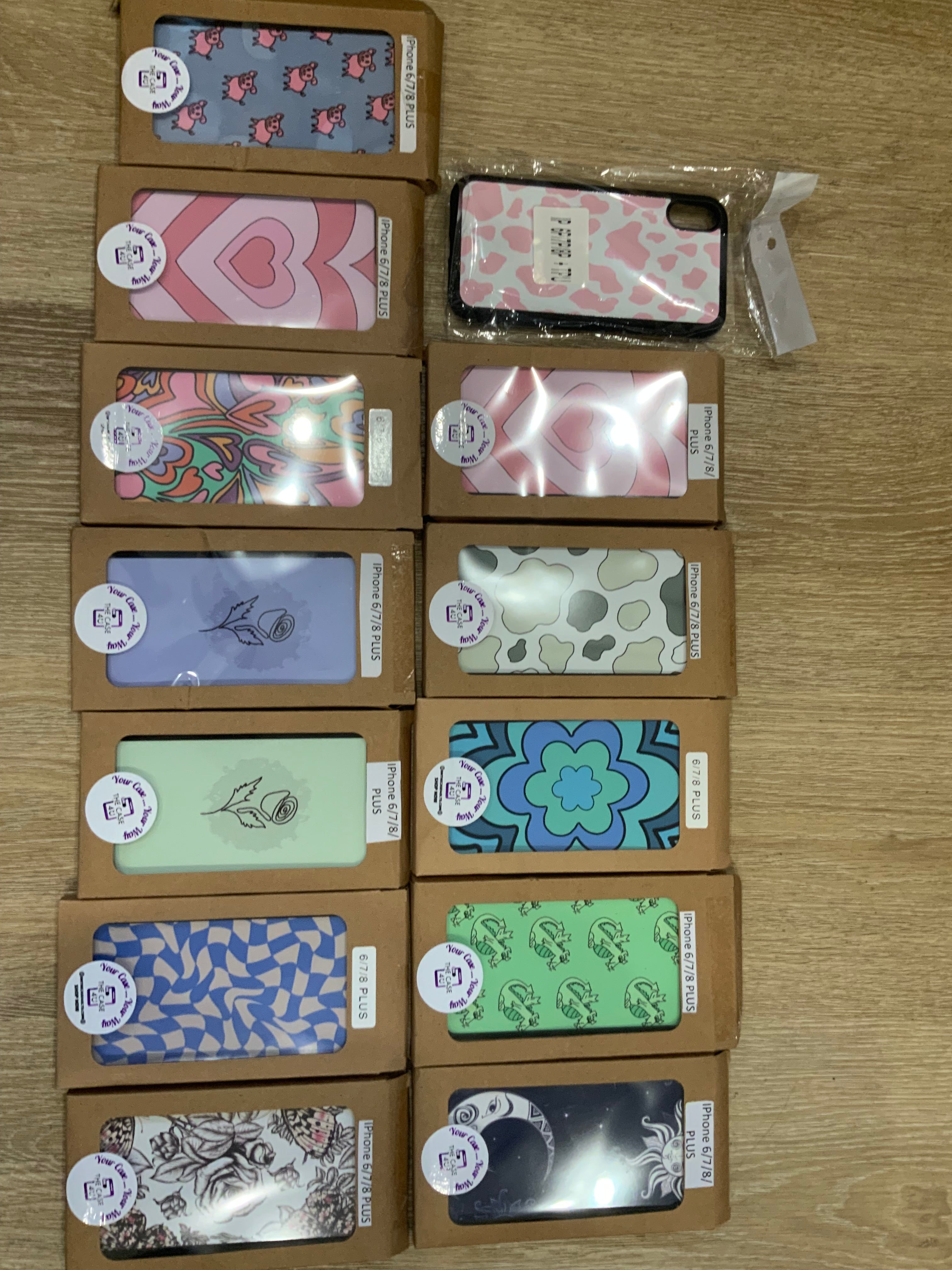 A collection of various phone cases with different floral and pattern designs, displayed in a row with their individual price tags.